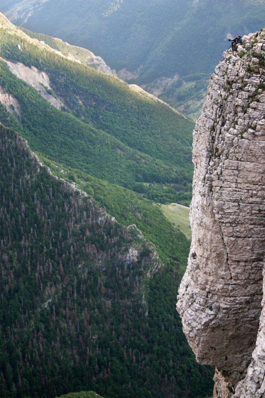 Jean-Michel Bertrand, assi sur une vire au bord du vide, en train de filmer l'aigle royal Vertige sur rencontre, film sur l'aigle royal