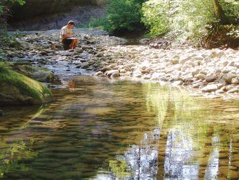 Pierre Baumgart en train de dessiner au bord de la rivière. / © Laurent Willenegger