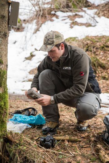 René Gadient, de l'Office cantonal de la chasse et de la pêche relevant un piège photo. Reportage autour des loups du Calanda dans les Grisons - La Salamandre garde-faune piège photo René Gadient